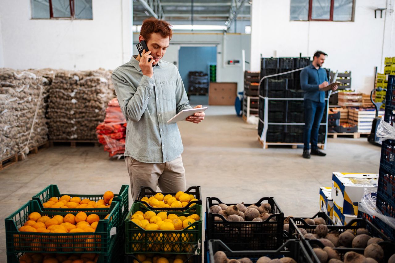 Travailleurs d'entrepôt contrôlant inventaire et produits frais avec technologie, illustrant la RSE durable dans l'agroalimentaire 2025